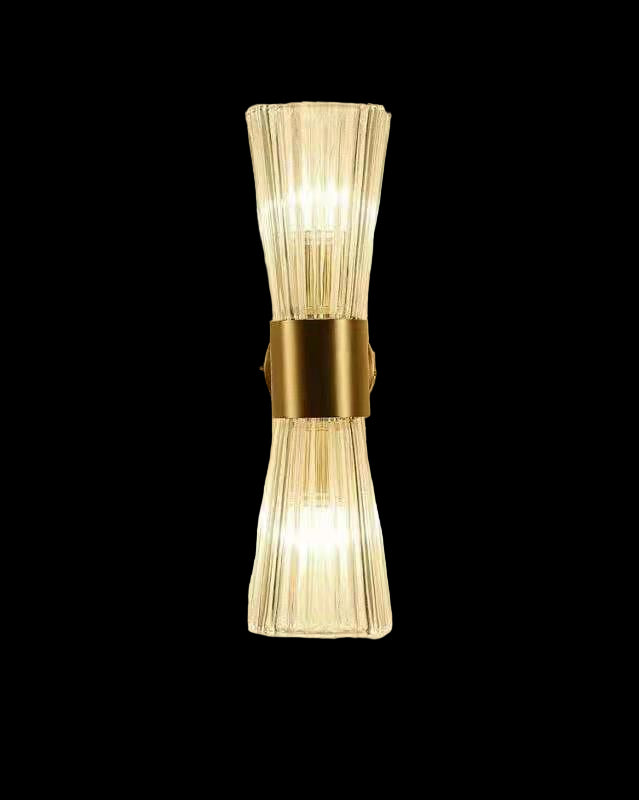 Wall-mounted light fixture with clear glass shade and gold metal base on a beige wall.